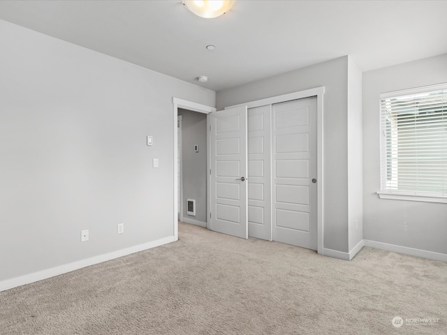 unfurnished bedroom with a closet and light colored carpet