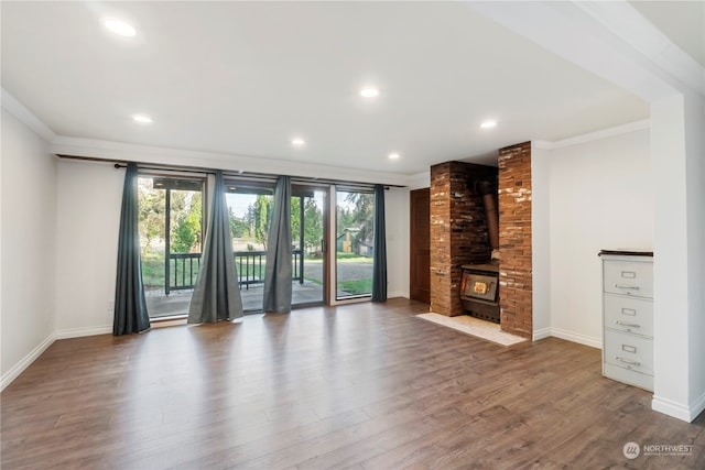 unfurnished living room with ornamental molding, hardwood / wood-style floors, and a wood stove