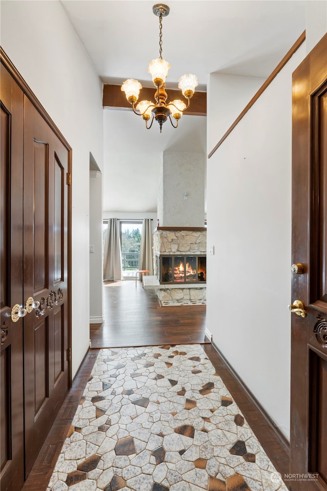 entryway featuring a fireplace, a chandelier, and dark hardwood / wood-style flooring