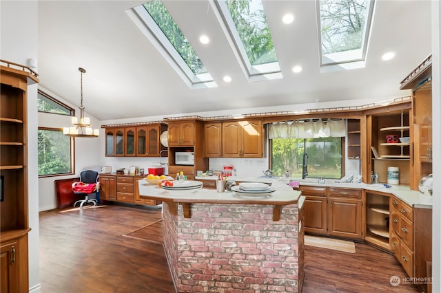 kitchen with a healthy amount of sunlight, a kitchen island, pendant lighting, and a skylight