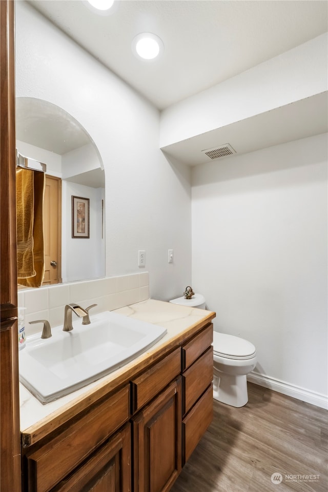 bathroom featuring wood-type flooring, vanity, and toilet