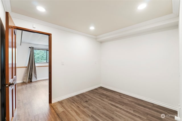 spare room featuring wood-type flooring and crown molding