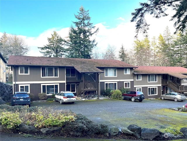 view of front of home with stairs and a shingled roof