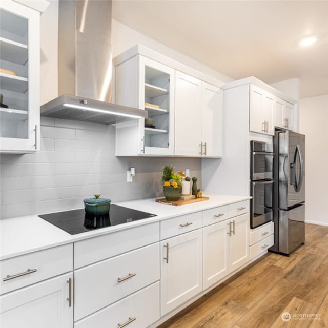 211 179th St SE, Bothell, WA 98021 - kitchen featuring wall chimney exhaust hood, appliances with stainless steel finishes, white cabinets, light wood finished floors, and backsplash