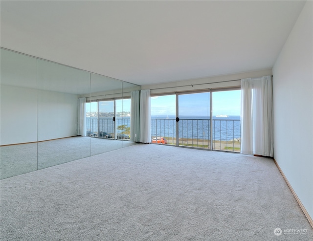 unfurnished room with a water view and carpet floors