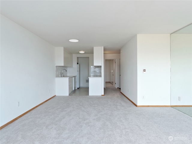 unfurnished living room with light carpet and sink