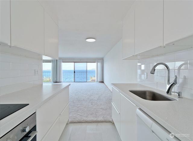 kitchen featuring sink, backsplash, white cabinetry, dishwasher, and a water view