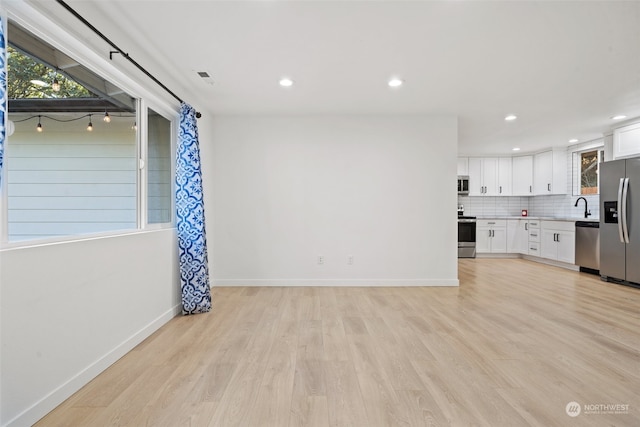 unfurnished living room with sink and light hardwood / wood-style floors