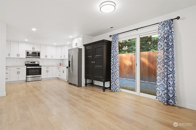 kitchen with backsplash, light hardwood / wood-style flooring, stainless steel appliances, and white cabinets