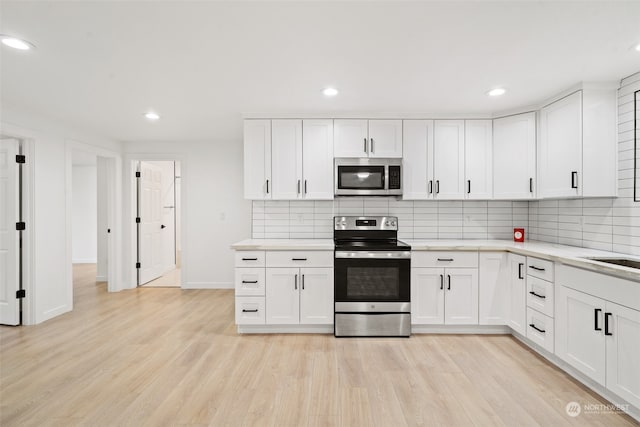 kitchen with light hardwood / wood-style flooring, white cabinetry, and appliances with stainless steel finishes