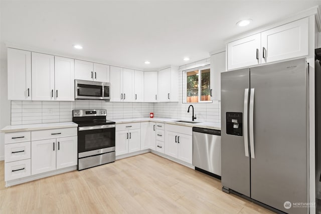 kitchen featuring white cabinets, appliances with stainless steel finishes, sink, and light hardwood / wood-style flooring