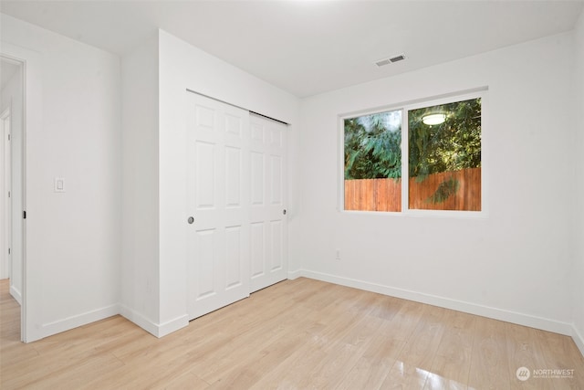 unfurnished bedroom featuring light hardwood / wood-style floors and a closet