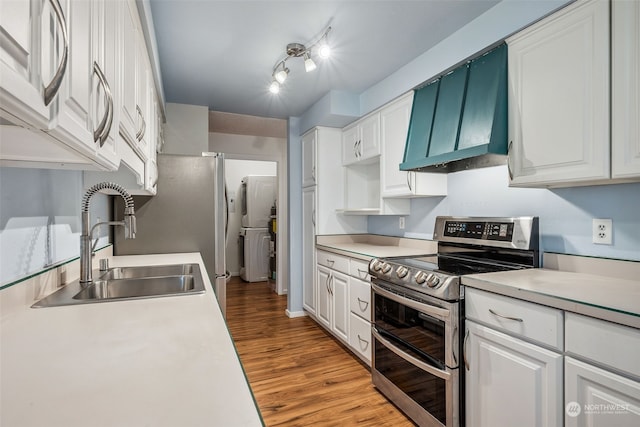 kitchen featuring white cabinets, premium range hood, sink, stainless steel range with electric stovetop, and light hardwood / wood-style floors