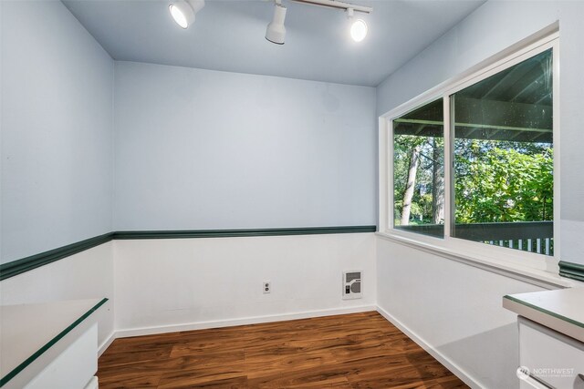 empty room with heating unit, rail lighting, and dark hardwood / wood-style flooring