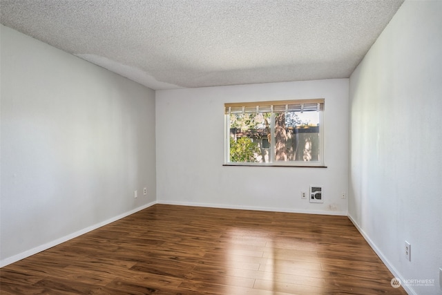 unfurnished room with a textured ceiling and dark hardwood / wood-style flooring