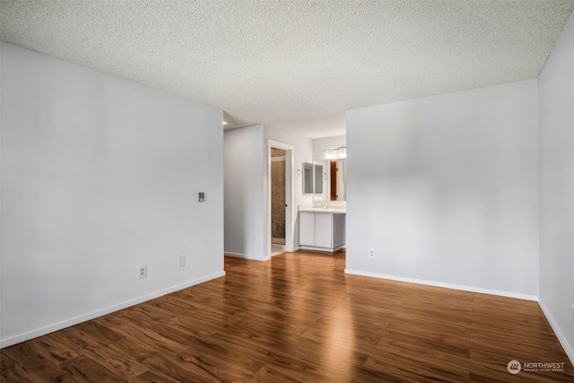 empty room with a textured ceiling, dark hardwood / wood-style floors, and sink