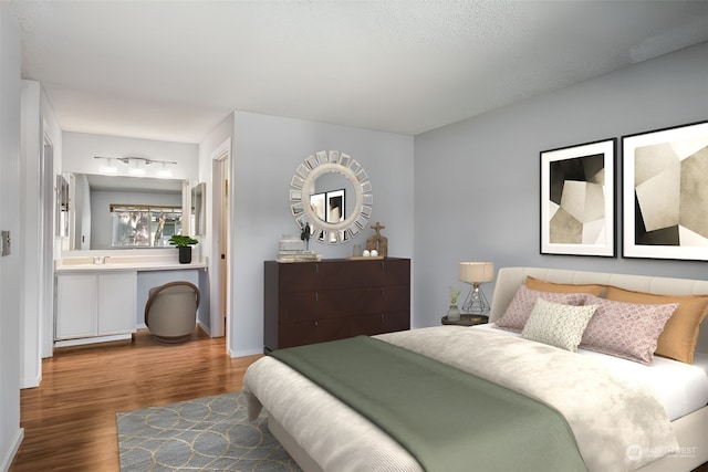 bedroom with a textured ceiling, connected bathroom, sink, and hardwood / wood-style flooring