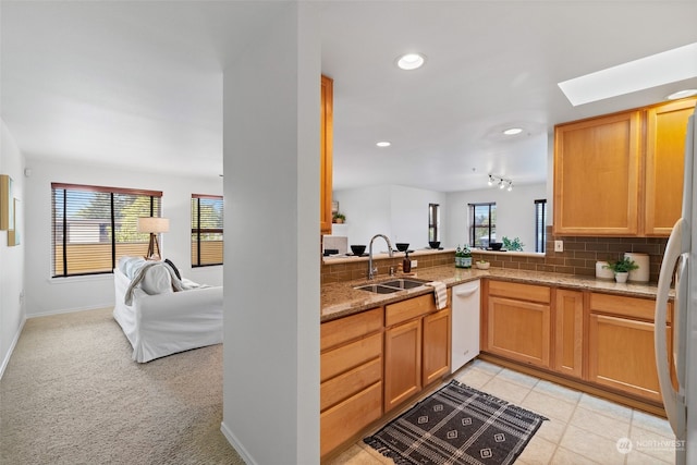 kitchen with sink, white appliances, backsplash, light colored carpet, and light stone countertops