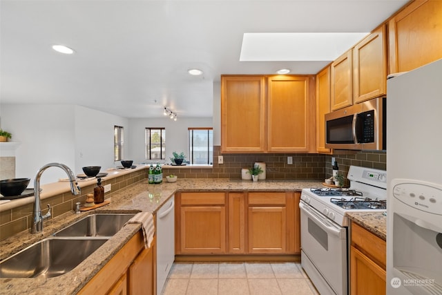 kitchen featuring light tile patterned floors, sink, white appliances, backsplash, and light stone countertops