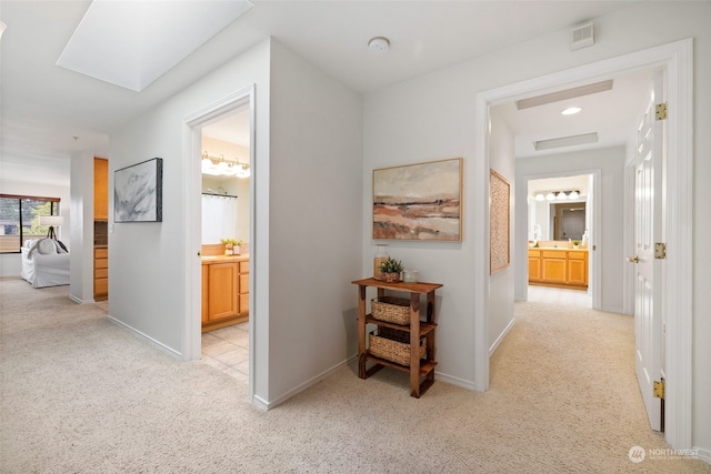 corridor with a skylight and light colored carpet