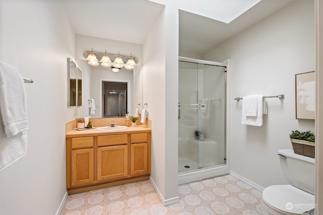 bathroom featuring a skylight, vanity, toilet, and a shower with door