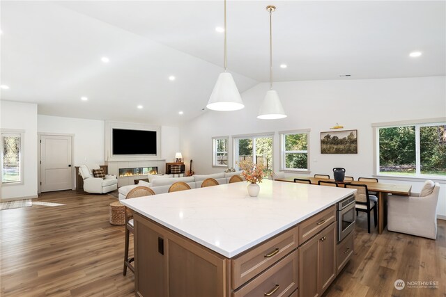 kitchen featuring pendant lighting, dark wood-type flooring, a center island, a breakfast bar area, and stainless steel microwave