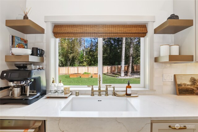 kitchen featuring backsplash, light stone counters, and sink