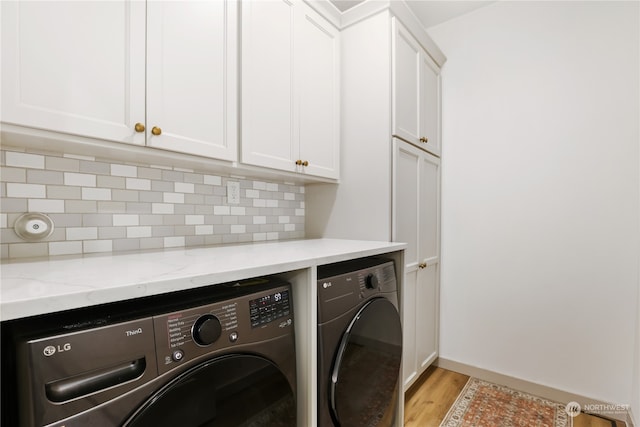 laundry area featuring cabinets, light hardwood / wood-style flooring, and washer and clothes dryer