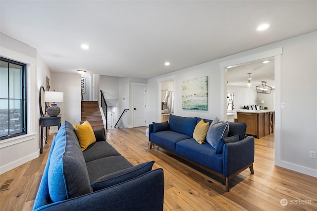 living room with light hardwood / wood-style floors and a notable chandelier