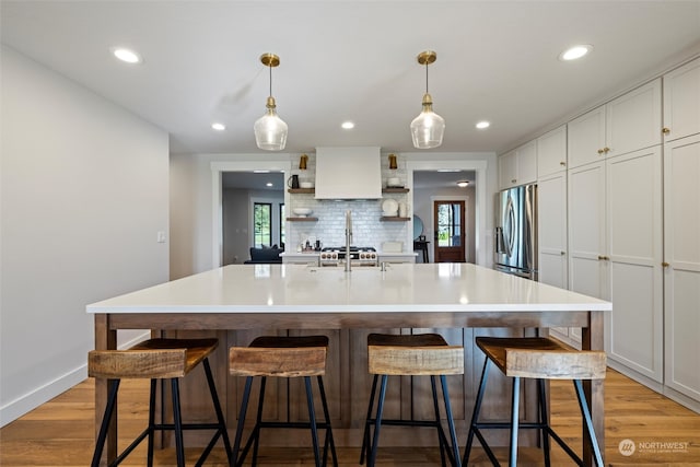 kitchen featuring a kitchen island with sink, stainless steel fridge, plenty of natural light, and light hardwood / wood-style flooring