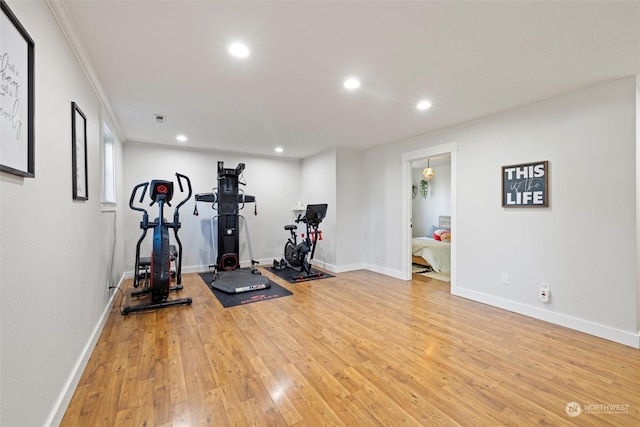 workout area with light wood-type flooring and ornamental molding