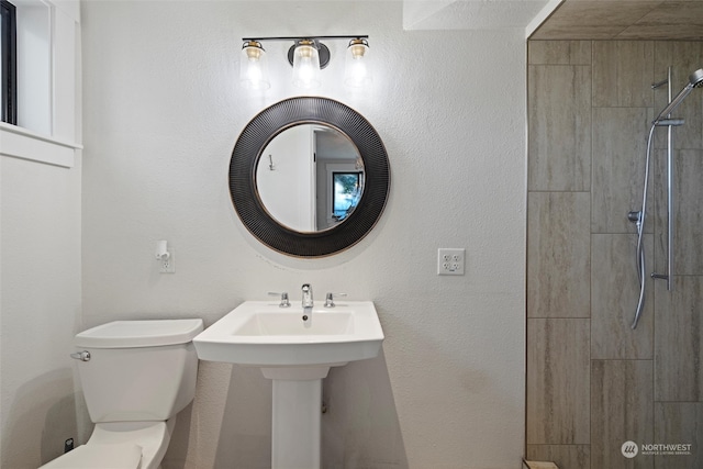 bathroom with a tile shower and toilet