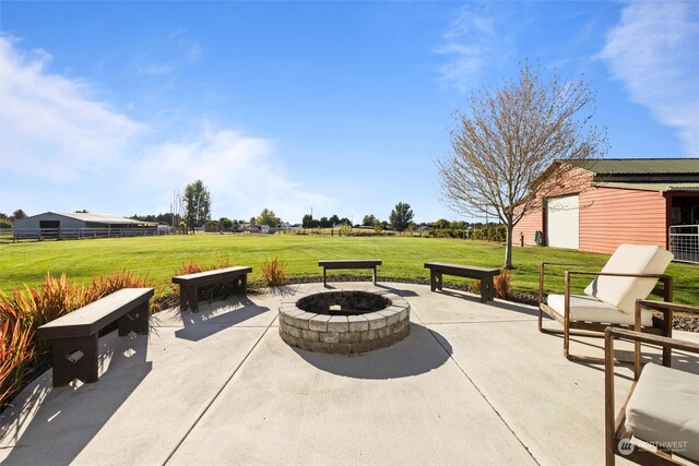 view of patio featuring a garage, an outdoor structure, and a fire pit