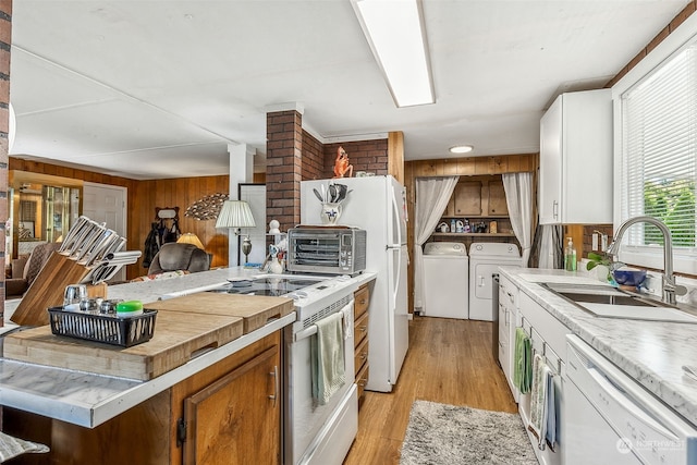 kitchen featuring white cabinetry, independent washer and dryer, white appliances, light hardwood / wood-style flooring, and wooden walls