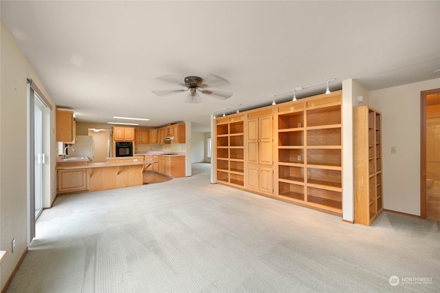 unfurnished living room featuring ceiling fan, sink, and light colored carpet