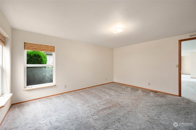 carpeted empty room featuring a textured ceiling