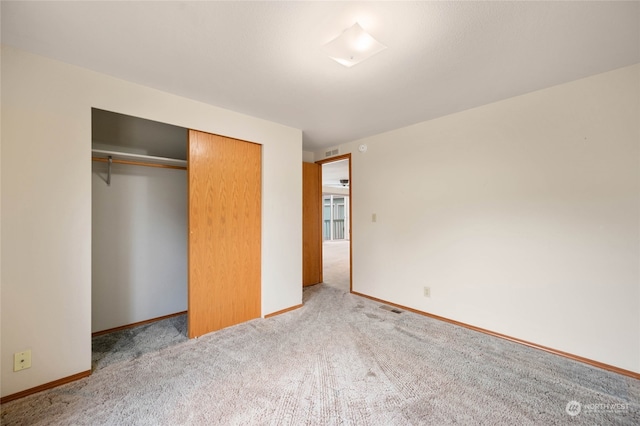 unfurnished bedroom with a closet and light colored carpet