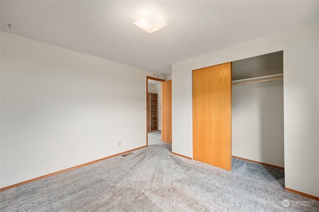 unfurnished bedroom with light colored carpet and a closet