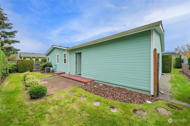 rear view of house featuring central AC unit, a yard, and a patio