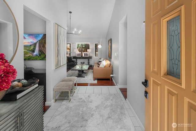 entrance foyer with an inviting chandelier, light hardwood / wood-style flooring, and vaulted ceiling