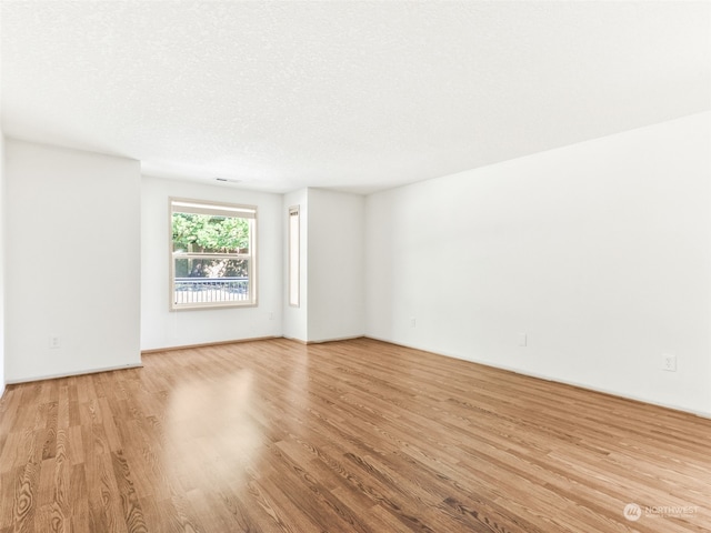 empty room featuring a textured ceiling and light hardwood / wood-style floors