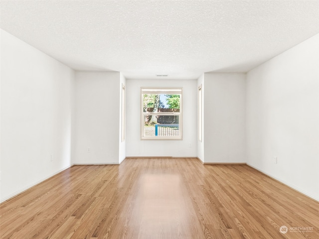 unfurnished room featuring a textured ceiling and light hardwood / wood-style flooring