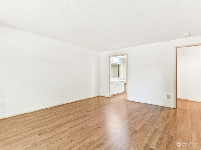 spare room with light hardwood / wood-style floors and a textured ceiling