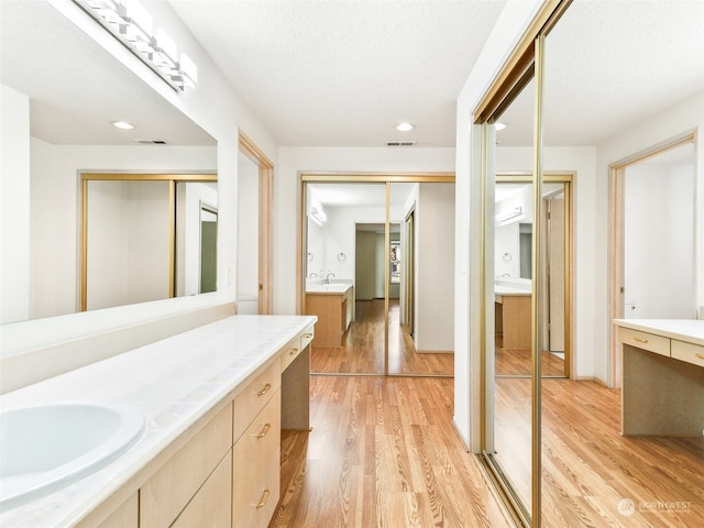 bathroom featuring wood-type flooring, vanity, and a textured ceiling