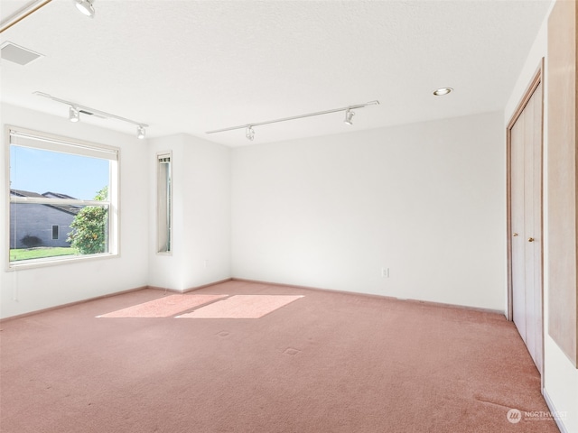 spare room featuring track lighting and light carpet