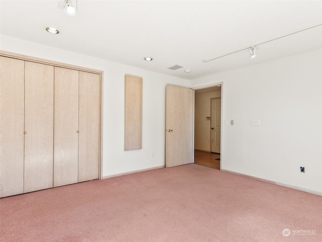 unfurnished bedroom featuring light colored carpet and a closet