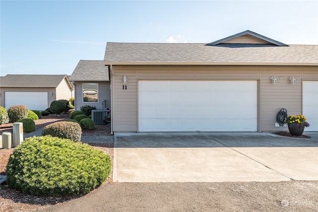 single story home with a garage and central air condition unit