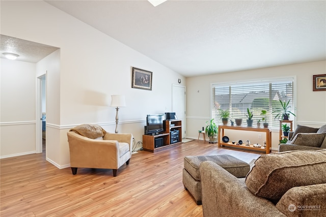 living room with light hardwood / wood-style flooring, vaulted ceiling, and a textured ceiling