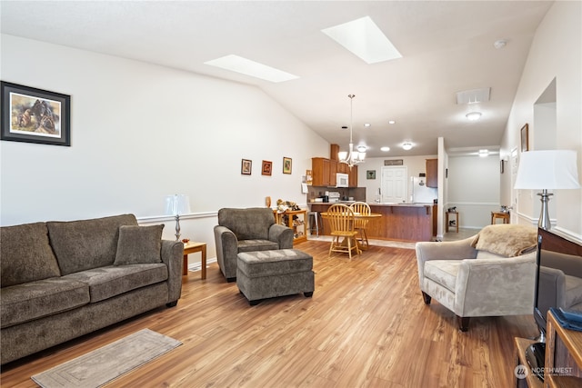 living room with a notable chandelier, light hardwood / wood-style floors, and lofted ceiling with skylight