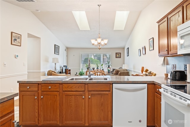 kitchen featuring vaulted ceiling with skylight, white appliances, a chandelier, and decorative light fixtures